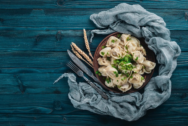 Saborosos bolinhos de carne caseiros de farinha integral ou pelmeni russo polvilhado com salsa fresca no prato na mesa de madeiracopy espaço vista de cima