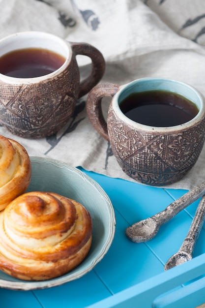 Saborosos bolos com geléia e duas xícaras de chá em madeira azul. Em seguida, há duas colheres e um guardanapo de linho leve.