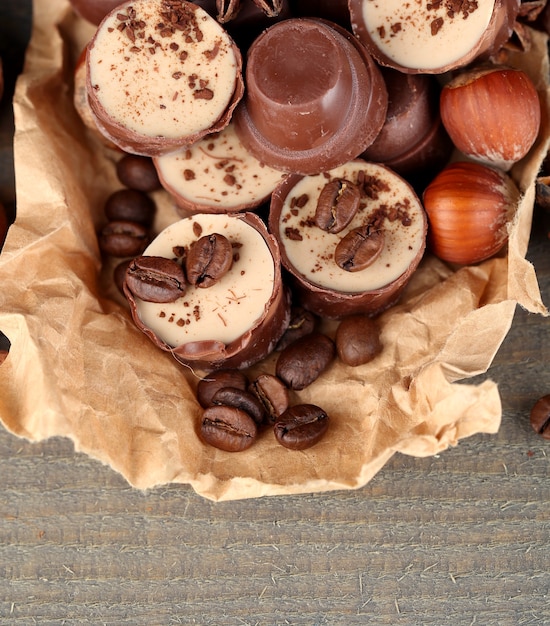 Saborosos bombons de chocolate com grãos de café e nozes em fundo de madeira