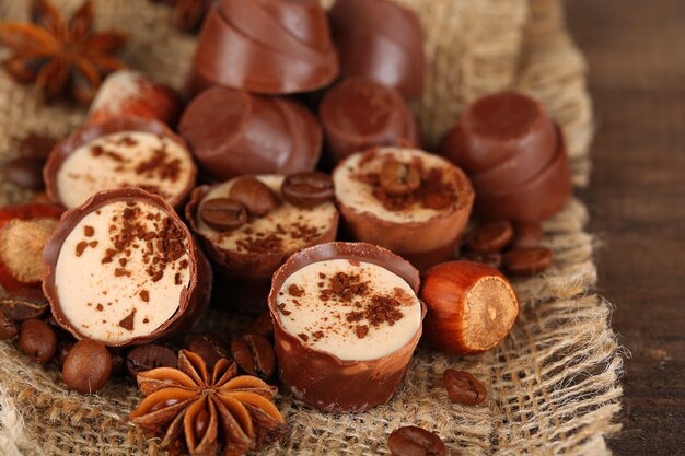 Saborosos bombons de chocolate com grãos de café e nozes na mesa de madeira