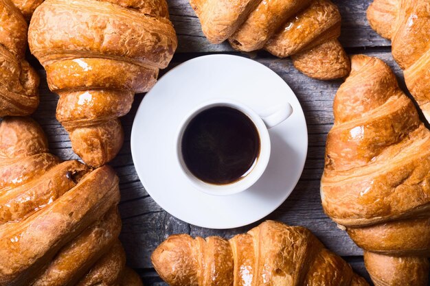 Saborosos croissants amanteigados e café na velha mesa de madeira