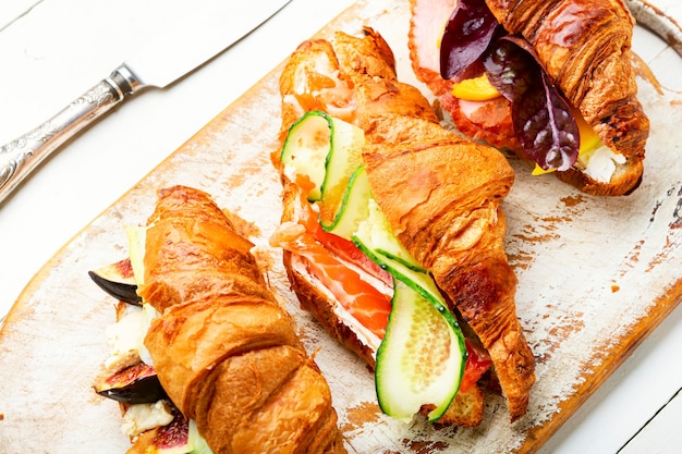 Saborosos croissants com recheio salgado. Croissants com salmão, bacon, figos e pepino