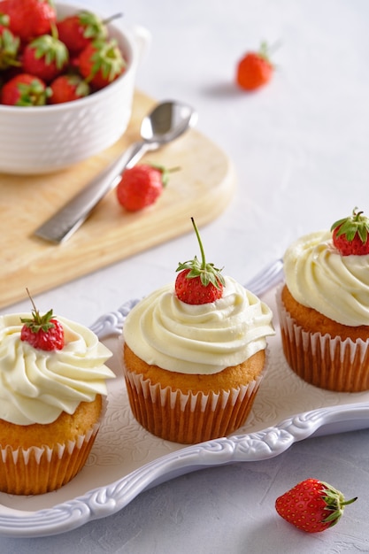 Saborosos cupcakes com morangos e creme suave em um fundo branco