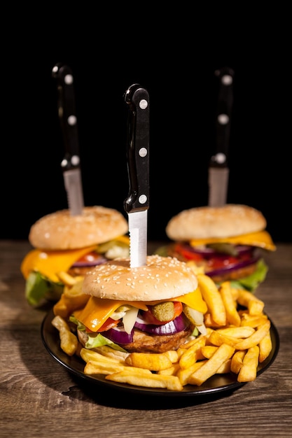 Foto saborosos hambúrgueres gourmet deliciosos em chapa preta ao lado de batatas fritas. comida rápida. lanche não saudável