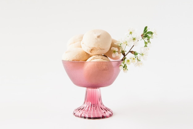 Saborosos marshmallows em um vaso violeta e flores. Superfície branca. Minimalismo. Espaço para texto