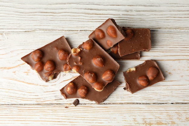 Saborosos pedaços de chocolate na mesa de madeira branca