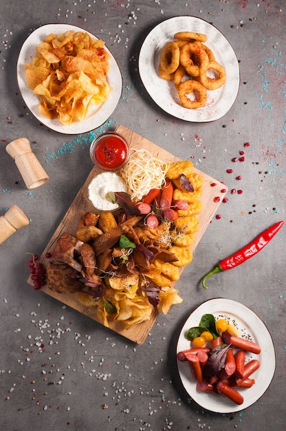 Saborosos petiscos de cerveja variada: batatas fritas, salsichas, anéis de cebola, nuggets de frango, croutons, costelas defumadas, asas de frango, molho de tomate e alho