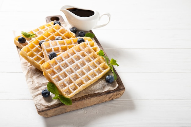 Saborosos waffles com geléia e mirtilos. No fundo de madeira