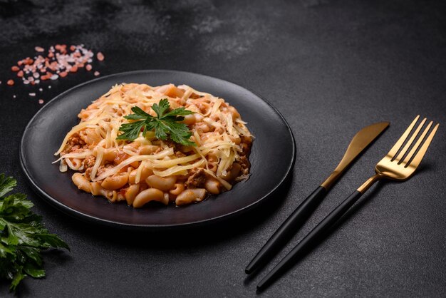 Sabrosa y apetitosa pasta italiana clásica con salsa de tomate y queso en un plato de fondo oscuro