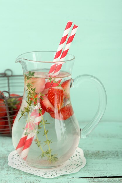 Sabrosa bebida fresca con fresas y tomillo sobre fondo de madera