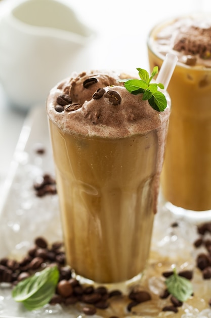 Sabrosa bebida refrescante fría con café, leche, helado de chocolate y hielo en el vidrio sobre fondo de hielo. De cerca.