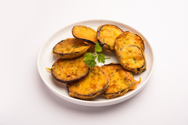 Sabrosa berenjena Pakora o crujientes buñuelos de berenjena, merienda india a la hora del té servida con chutney verde