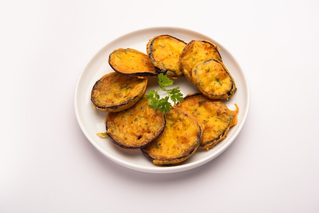 Sabrosa berenjena Pakora o crujientes buñuelos de berenjena, merienda india a la hora del té servida con chutney verde