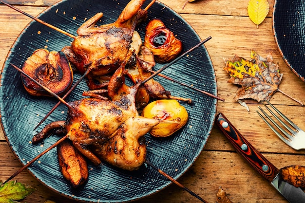 Sabrosa codorniz casera a la plancha sobre brochetas en salsa de frutas.