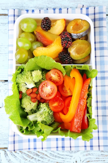 Sabrosa comida vegetariana en caja de plástico sobre mesa de madera