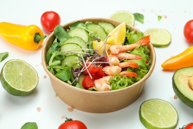 Sabrosa ensalada de camarones e ingredientes sobre fondo blanco.