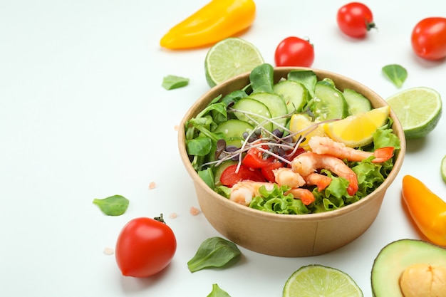 Foto sabrosa ensalada de camarones e ingredientes sobre fondo blanco.