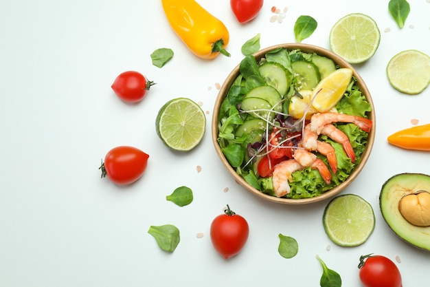 Sabrosa ensalada de camarones e ingredientes sobre fondo blanco.