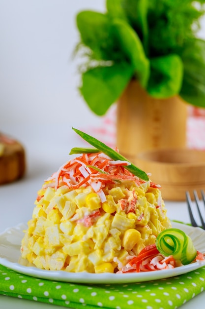 Sabrosa ensalada con carne de cangrejo, maíz, pepino y huevos. Foto vertical.