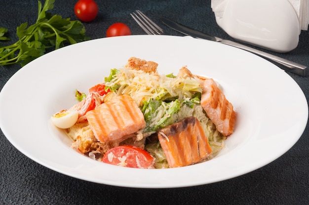 Sabrosa ensalada César con salmón a la plancha en un plato blanco sobre fondo negro