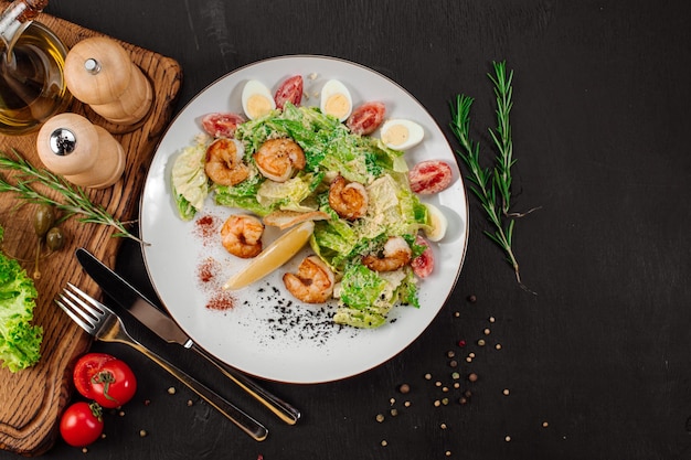 Sabrosa ensalada con gambas, hierbas y verduras sobre fondo negro