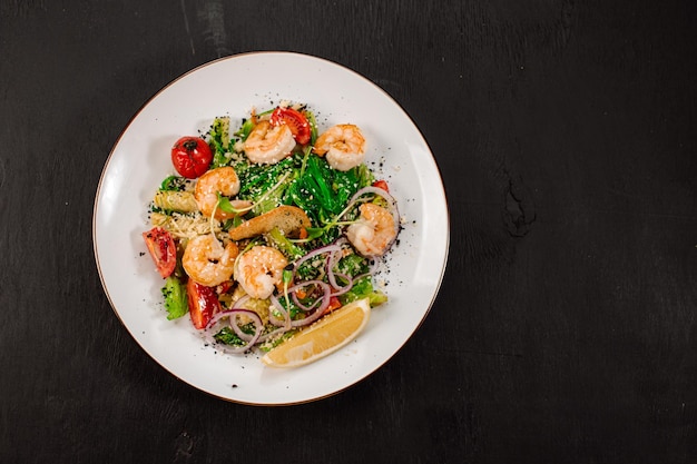 Sabrosa ensalada con gambas, hierbas y verduras sobre fondo negro