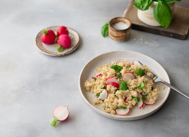 Sabrosa ensalada vegetariana con quinua, rábano fresco y albahaca sobre un muro de hormigón gris. concepto de alimentación saludable