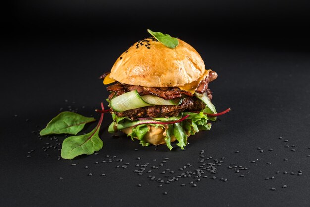 Sabrosa hamburguesa artesanal con carne a la parrilla, queso, tomate en el fondo negro