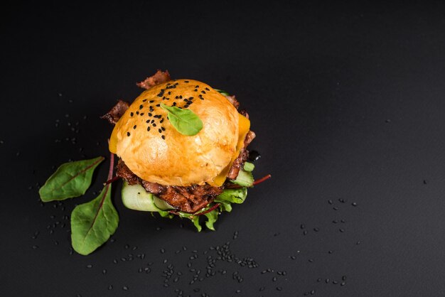 Sabrosa hamburguesa artesanal con carne a la parrilla, queso, tomate en el fondo negro