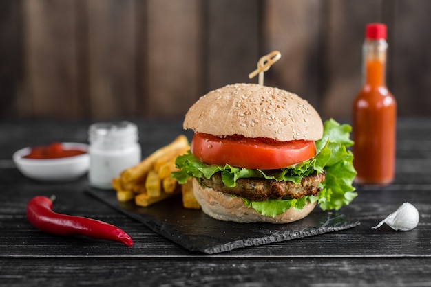 Sabrosa hamburguesa con carne y verduras sobre un fondo oscuro. Comida rápida. Se puede utilizar como fondo.