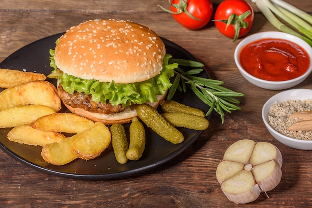 Sabrosa hamburguesa casera a la parrilla. Deliciosas hamburguesas a la parrilla. Craft burger y papas fritas en la mesa de madera