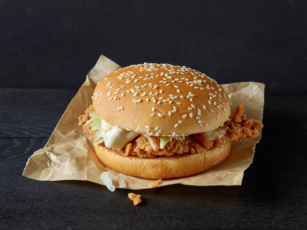 Sabrosa hamburguesa fresca con carne de pollo frito en mesa de madera negra