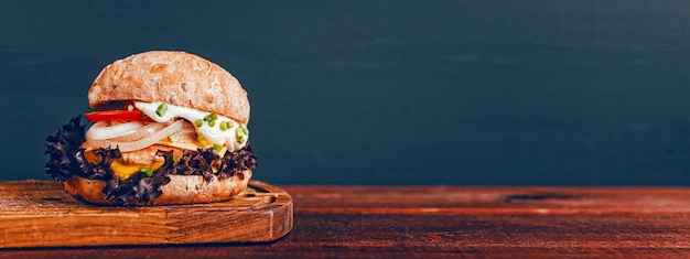 Sabrosa hamburguesa en tabla de cortar de madera