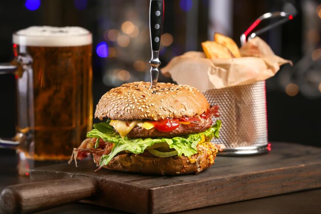 Sabrosa hamburguesa en tablero de madera sobre fondo oscuro