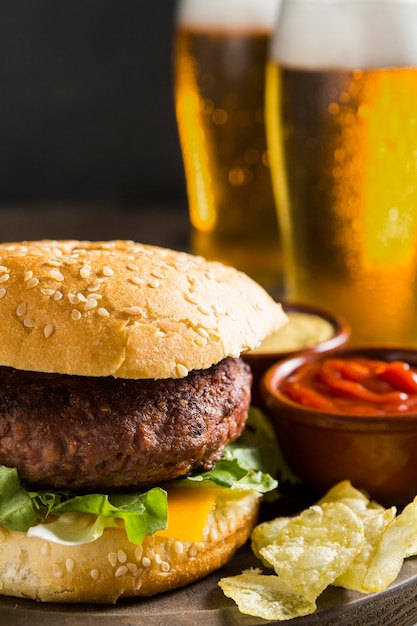 Sabrosa hamburguesa con vasos de cerveza y salsa de tomate