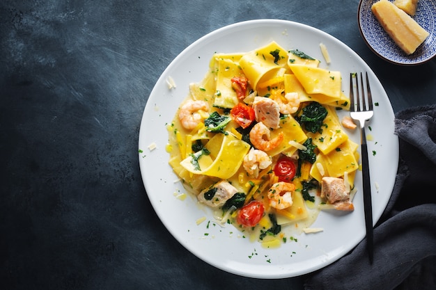 Sabrosa pasta apetitosa con camarones, verduras y espinacas servido en plato. Vista desde arriba.