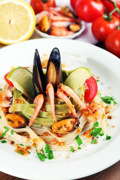 Sabrosa pasta con camarones mejillones tomates en plato sobre fondo de madera