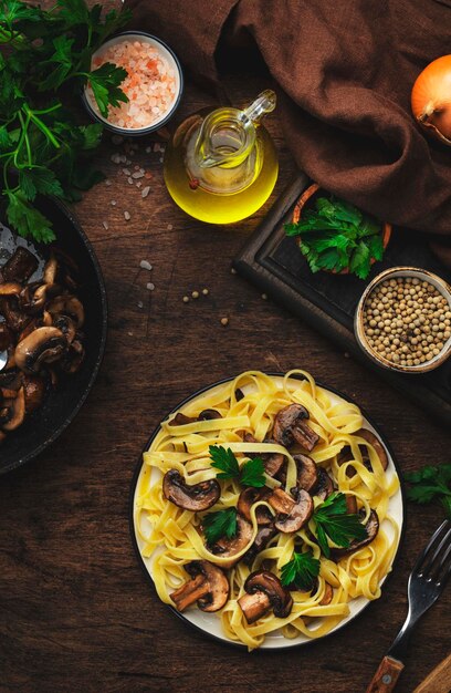 Sabrosa pasta fettuccine con champiñones servida en un plato con verduras y especias en la mesa de la cocina de madera rústica vista superior de fondo Cocina vegetariana saludable y comer concepto de comida italiana