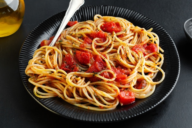 Foto sabrosa pasta italiana clásica con salsa de tomate y queso en un plato sobre fondo oscuro. vista superior.