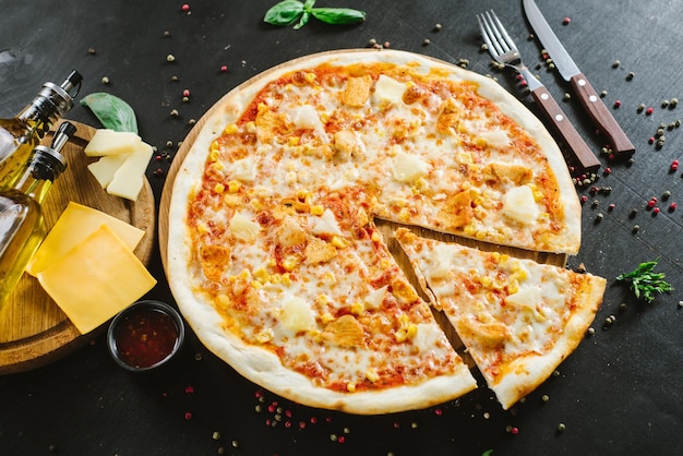 Sabrosa pizza con jamón, maíz y queso sobre fondo negro