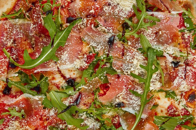 Sabrosa pizza con jamón serrano, rúcula y parmesano sobre una mesa blanca. Cocina tradicional italiana. Deliciosa comida plana yacía. Vista superior. Textura para 3d