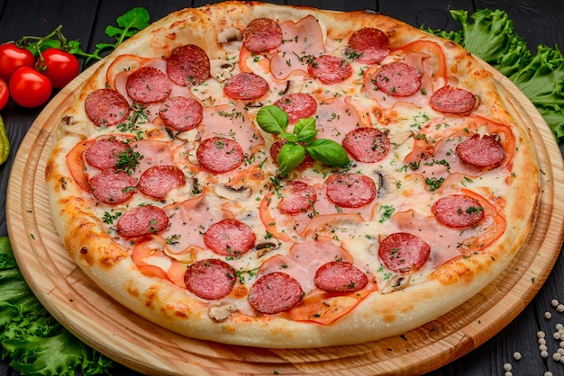 Sabrosa pizza de pepperoni e ingredientes para cocinar tomates albahaca sobre fondo de hormigón negro Vista superior de la pizza de pepperoni caliente Con espacio para copiar texto Plano