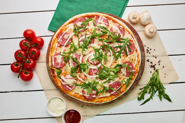 Sabrosa pizza de pepperoni recién horneada con queso mozzarella de salami y rukkola servida sobre fondo de madera con salsa de tomate y hierbas Concepto de entrega de alimentos Menú del restaurante