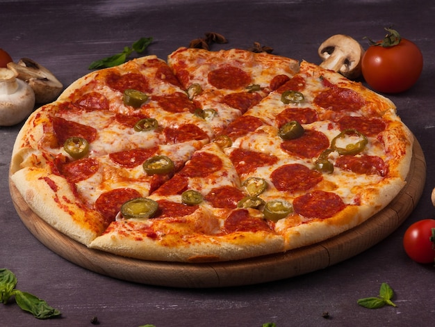 Sabrosa pizza picante con pepperoni y jalapeño en una tabla de madera
