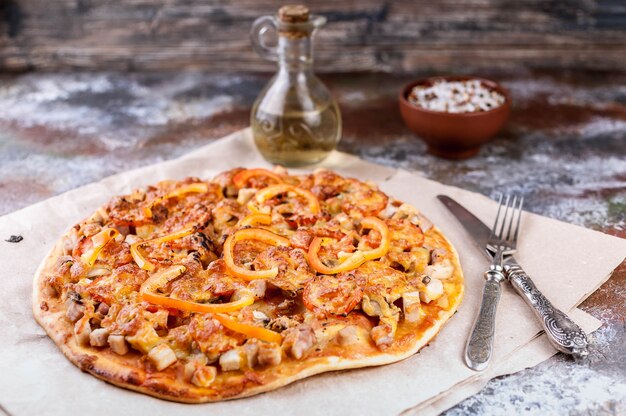 Foto sabrosa pizza con pollo, pimientos y queso sobre madera