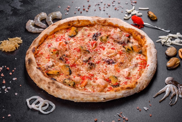 Sabrosa pizza en rodajas con mariscos y tomate sobre fondo negro. cocina mediterranea