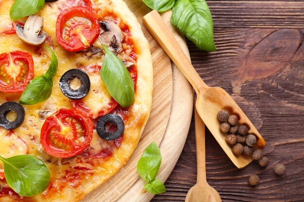 Sabrosa pizza con verduras y albahaca en la mesa de cerca