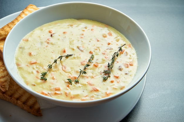 Sabrosa sopa de crema de queso con champiñones y tocino, crutones en un tazón blanco. Vista superior