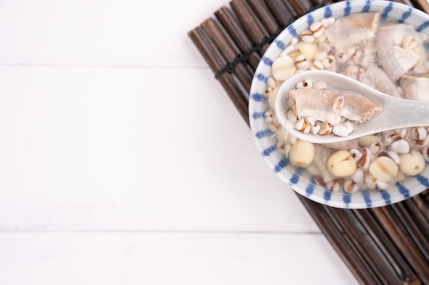 Foto sabrosa sopa de sabor a hierbas de cuatro tónicos, comida tradicional taiwanesa con hierbas, intestinos de cerdo en la mesa de madera blanca, de cerca, endecha plana, vista superior.