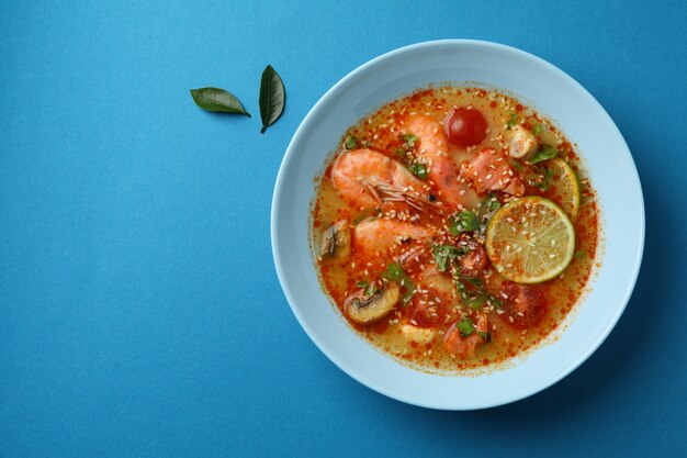 Sabrosa sopa Tom yum sobre fondo azul.